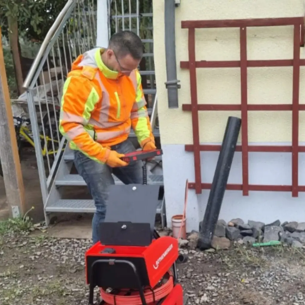 Mitarbeiter der TK-Rohrreinigung Fulda mit der Rohrkamera an einem Haus mit Fallrohr